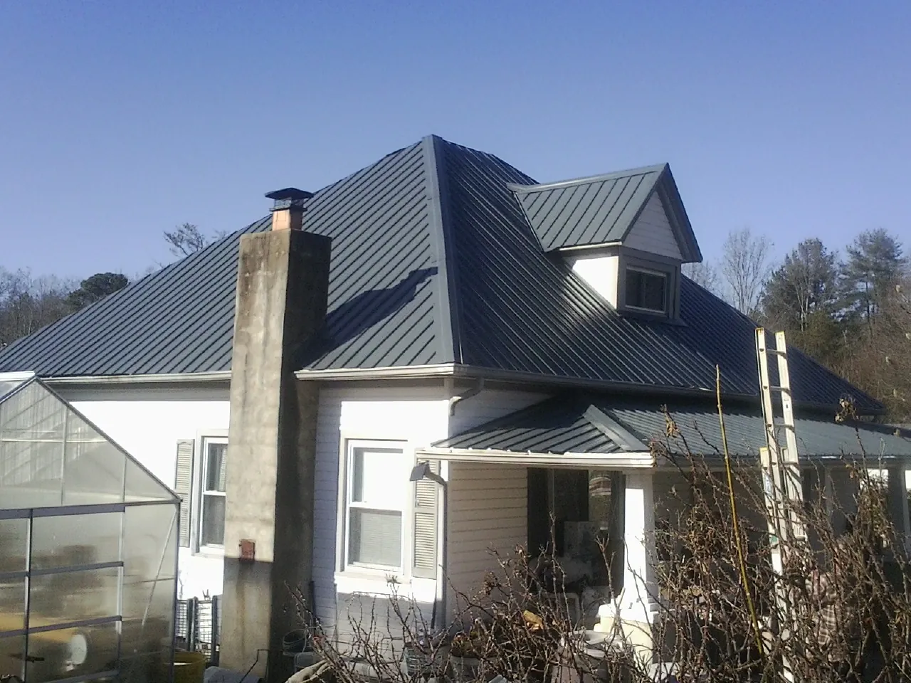 Dark blue standing seam metal roof on a white farmhouse with dormer — Slate & Tile Roof Repair by Roofing Brothers in Bargersville