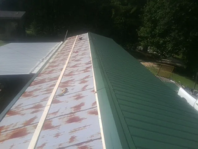 Old rusted panels beside newly installed green metal roofing — Wind Damage Roof Repair by Roofing Brothers in Bargersville