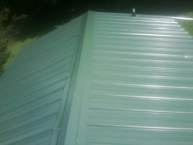 New green metal panels meeting at the ridge of a roof — Flat Roof Repair work by our crew in Bargersville