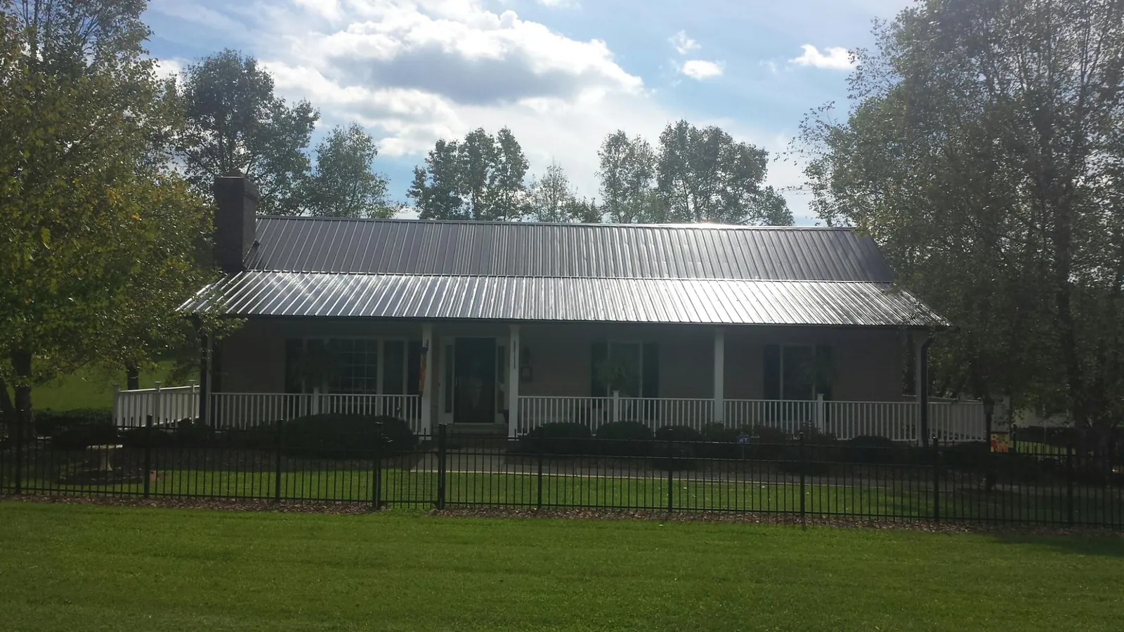 Gray metal roof on a brick ranch with a full width front porch — Gutter Guard Installation work by our crew in Bargersville