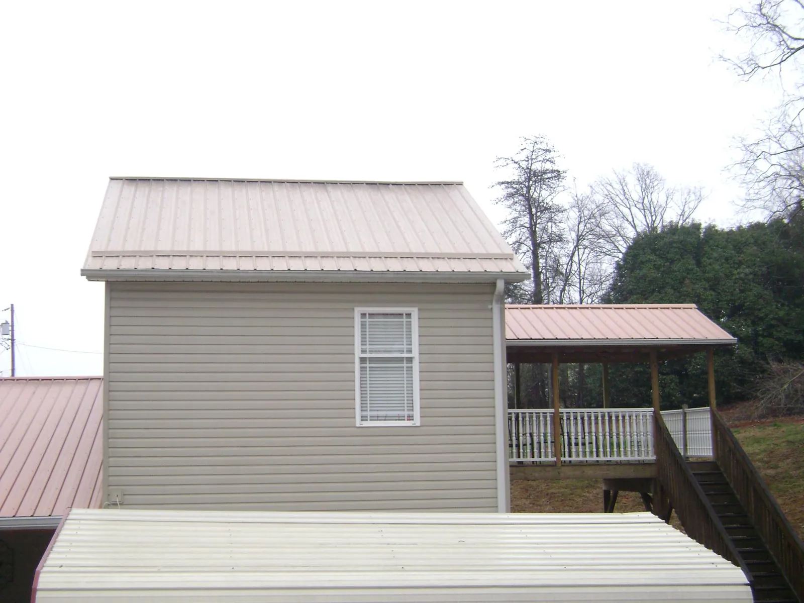 Tan metal roofs on a two story addition and attached porch, from a Roof Replacement job in Bargersville