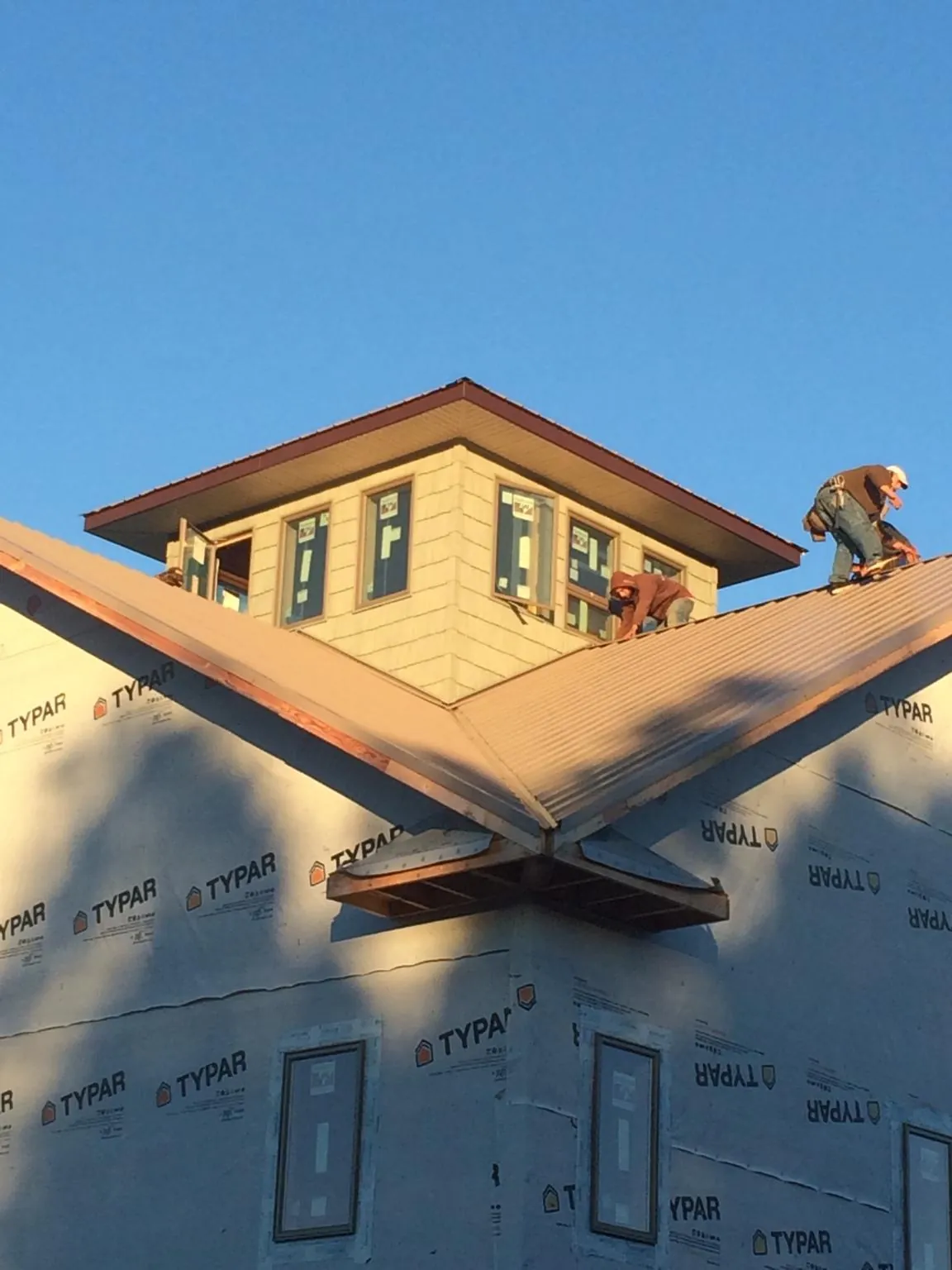 Roofers working around a rooftop cupola on a new metal roof at sunset — Roof Waterproofing in Bargersville by Roofing Brothers